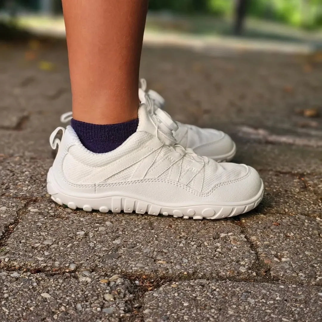 Niña usando calzado barefoot blanco en el parque