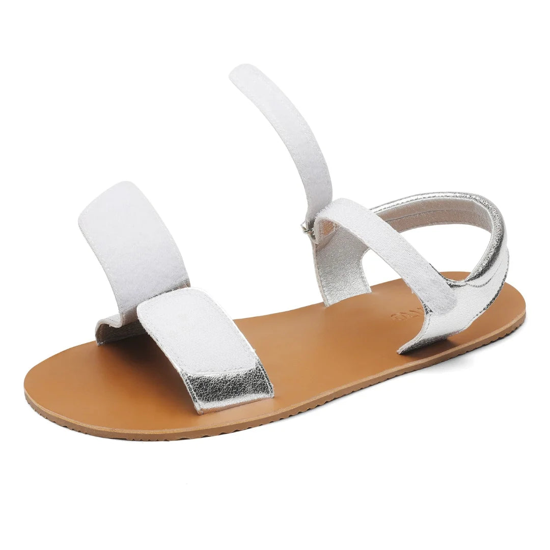 Detalle del doble cierre de velcro abierto en sandalia barefoot plateada para fácil calce.