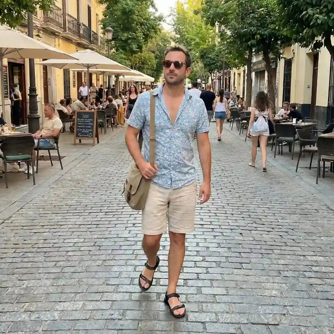 Hombre usando sandalias barefoot Sowilo Raido negras caminando en ciudad.