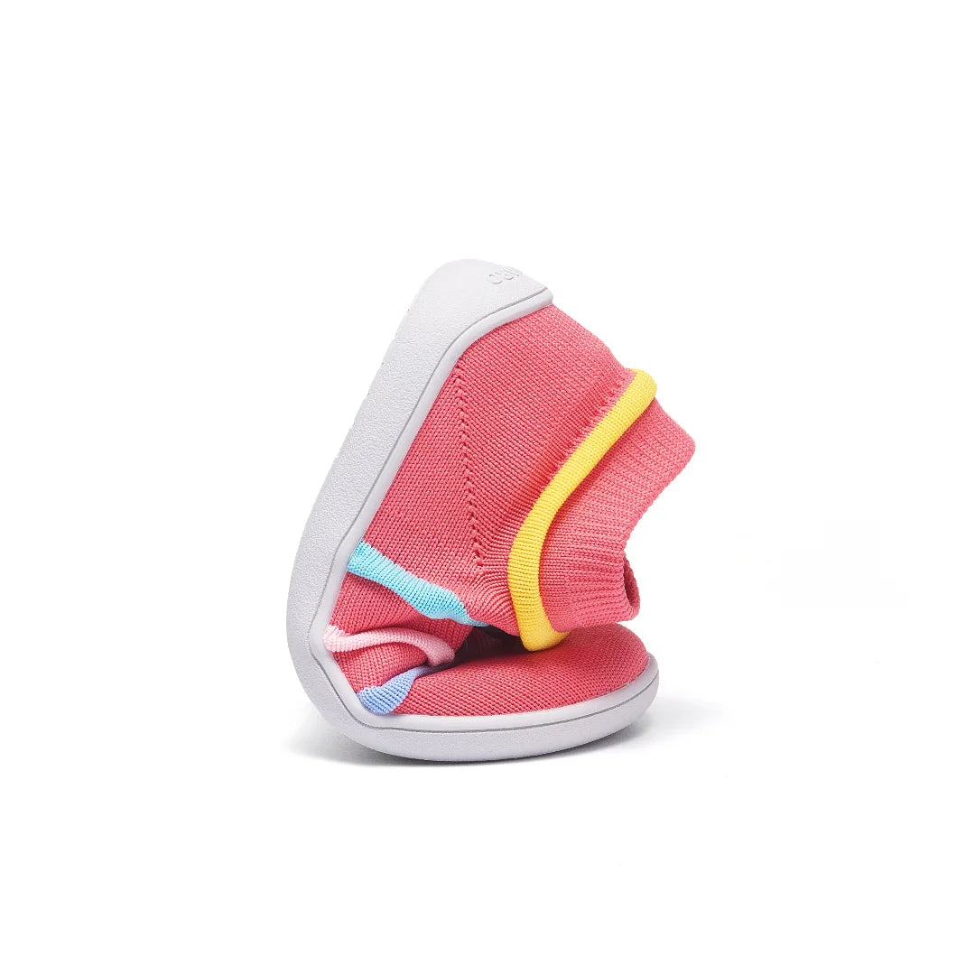 Zapatilla infantil rosa flexionada demostrando ligereza extrema.